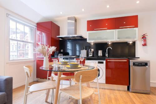 a kitchen with red cabinets and a table and chairs at Bright Carnaby Soho 1BR Apartment with AC in London
