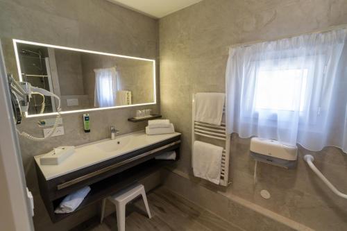 a bathroom with a sink and a mirror at Logis Hotel Arc En Ciel in Thonon-les-Bains