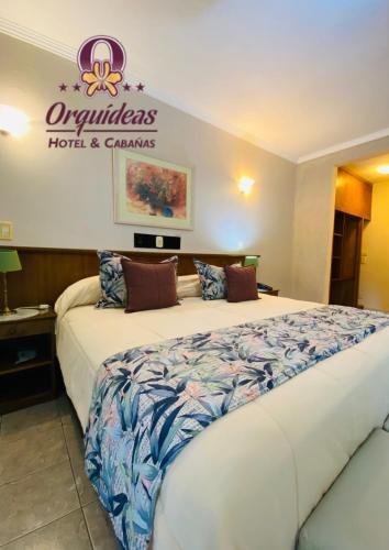 a large bed in a hotel room with a sign on the wall at Orquideas Hotel & Cabañas in Puerto Iguazú
