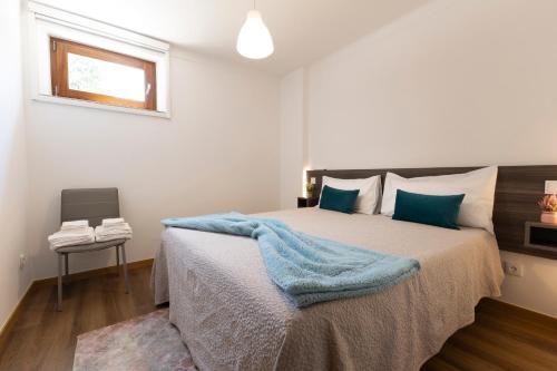 a bedroom with a bed with a blue blanket on it at A Trajadinha do Lima in Ponte de Lima