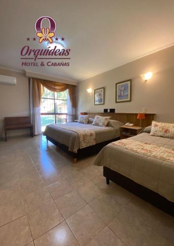 a hotel room with two beds and a sign on the wall at Orquideas Hotel & Cabañas in Puerto Iguazú