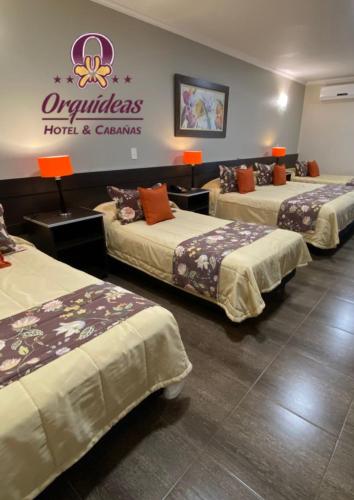 a hotel room with three beds and a sign on the wall at Orquideas Hotel & Cabañas in Puerto Iguazú