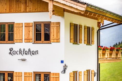 a white house with wooden windows and a sign at Lacklehen in Ramsau