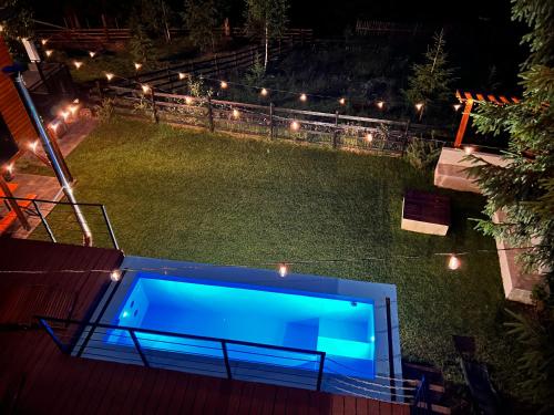 a blue swimming pool on the roof of a house at night at Chalet A Baisoara - Luxury A-Frame cu Piscină Încălzită in Băişoara