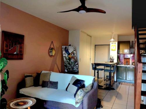 Una sala de estar con un sofá y un ventilador de techo. en K a Z - L'Ara Bleu, en Saint-Denis