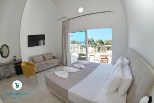 a white bedroom with a large bed and a living room at La SkalaVista in Skala Kefalonias
