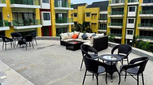 a patio with a couch and tables and chairs at The Tribe - by Kudrat's Nilaya with pool in Canacona