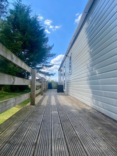 a wooden deck next to a building with a fence at Bynack Lodge in Boat of Garten