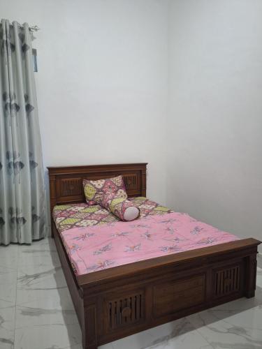 a wooden bed with a pillow on it in a room at NH Villa Lombok in Sangyang