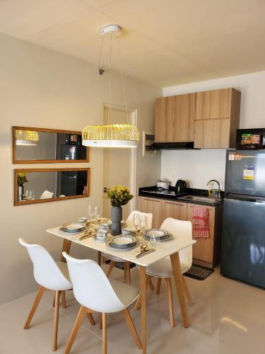 a kitchen with a table and white chairs in a kitchen at VERDANT by Vista Manors Deluxe Rooms with Balcony, Gym and Swimming Pool in Puerto Princesa City
