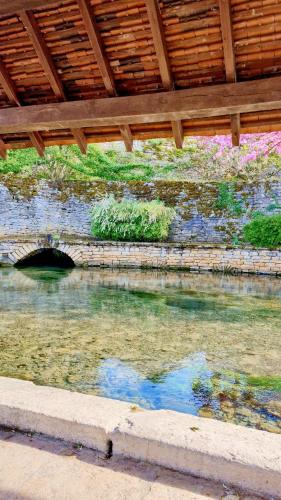 a body of water under a wooden roof at Caravane Zen & Jacuzzi proche des grottes de Bèze in Bèze