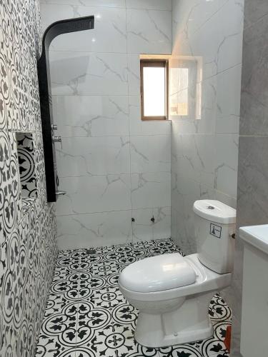a white bathroom with a toilet and a window at Bekouvi Smart Suite - City & Sea in Cotonou