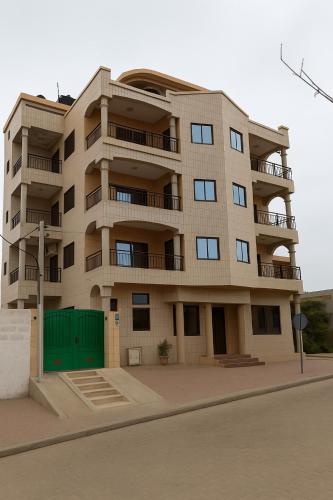a tall building with a green garage in front of it at Bekouvi Smart Suite - City & Sea in Cotonou