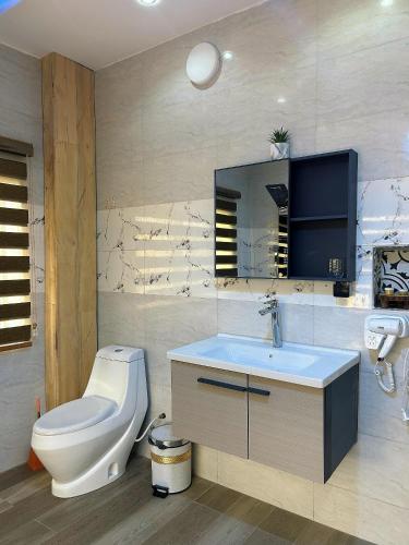 a bathroom with a toilet and a sink and a mirror at Bekouvi Smart Suite - City & Sea in Cotonou