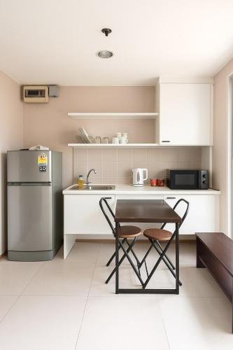 a small kitchen with a table and a refrigerator at Skyline View 1 Bedroom Near RCA, Thonglor And Nana in Bangkok