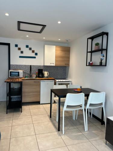 une cuisine avec une table noire et des chaises blanches dans l'établissement Dar Lila Cote d'Opale, à Saint-Martin-Boulogne