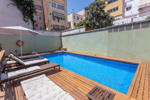 a swimming pool with two chairs and an umbrella at Apartment Barcelona Rentals - Gracia Pool Apartments Center in Barcelona