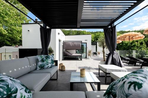 a patio with a couch and tables and an umbrella at Aqua Bluemica ADULTS ONLY in Międzyzdroje