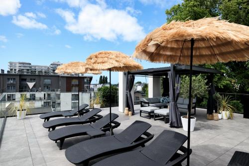 a group of lounge chairs and umbrellas on a roof at Aqua Bluemica ADULTS ONLY in Międzyzdroje