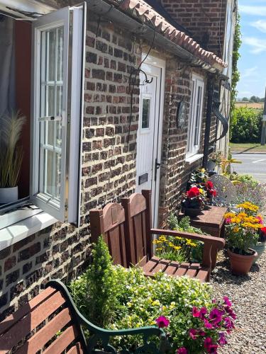 two benches sitting outside of a brick house with flowers at Yarm cottages Haystack Sleeps 2 Next to Fox Covert Pub in Kirk Leavington