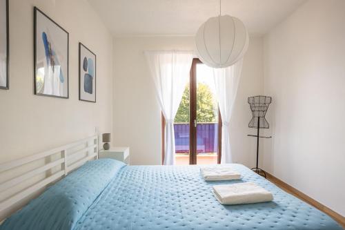 a bedroom with a blue bed with two towels on it at The Window on the Lake - Balcony Beaches Playground in Brusimpiano