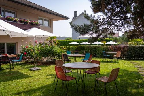 a patio with tables and chairs and umbrellas at Logis Hotel Arc En Ciel in Thonon-les-Bains