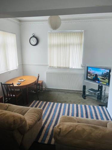 a living room with a table and a couch and a tv at Favourite Ensuite Room in Middlesbrough