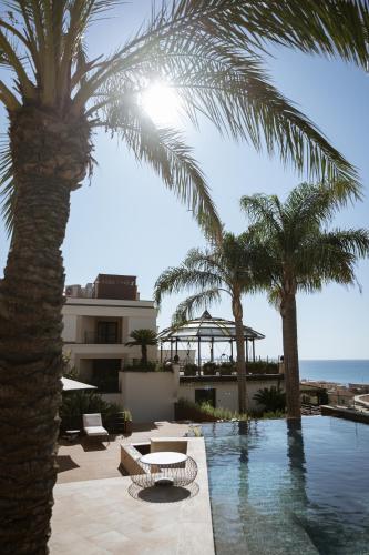 a resort with palm trees and a swimming pool at Villa Dei Melograni Boutique Hotel in Cefalù