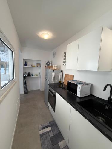 a kitchen with white cabinets and a microwave at Camilla Lipari House - Canneto in Lipari