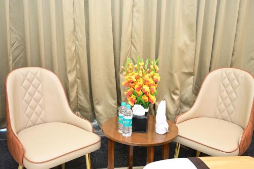 two chairs and a table with a vase of flowers at Aanvi Suites RR nagar in Bengaluru