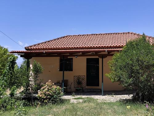 a small yellow house with a red roof at House by the River in Konitsa