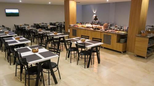 a restaurant with white tables and chairs and a counter at Hotel Greenville by Slim Hotéis in Primavera do Leste
