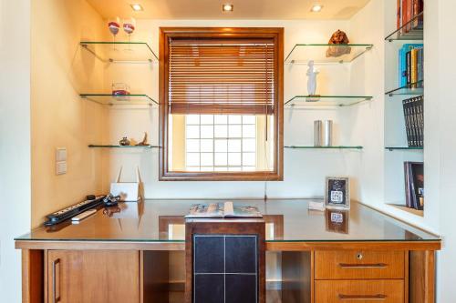Una cocina con un escritorio, una ventana y estantes. en Chris Sea View Apt with Hot Tub, en Gouves