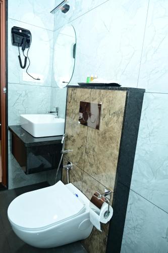 a bathroom with a white toilet and a sink at Aanvi Suites RR nagar in Bengaluru