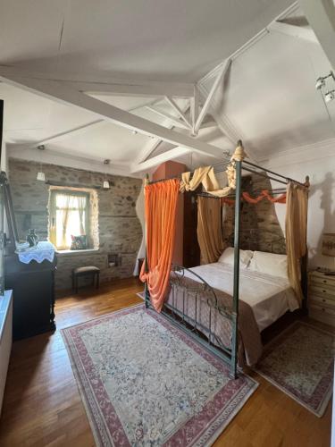 a bedroom with a four poster bed with an orange curtain at La Villa De Rosses- Sana Halkidiki in Saná