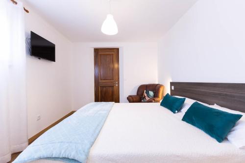a bedroom with a large bed with blue pillows at A Trajadinha do Lima in Ponte de Lima