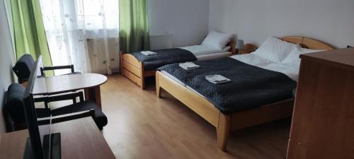 Habitación pequeña con 2 camas y mesa pequeña. en Willa Na Skarpie, en Krynica Morska
