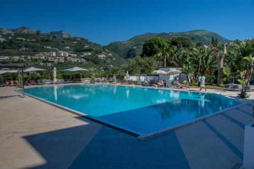 una grande piscina blu con montagne sullo sfondo di Grand Hotel Moon Valley a Vico Equense