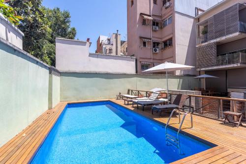 a swimming pool with a wooden deck next to a building at My Space Emirates - Bright Apartment in Gracia with shared Pool in Barcelona