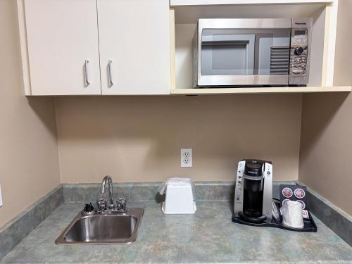 a kitchen counter with a sink and a microwave at Super 8 by Wyndham Edmonton South in Edmonton