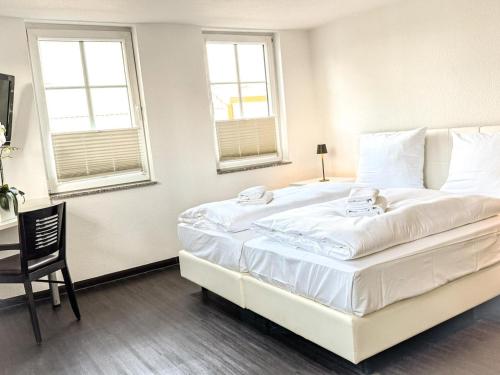 a large white bed in a room with two windows at Kretschmanns Hotel in Sehnde