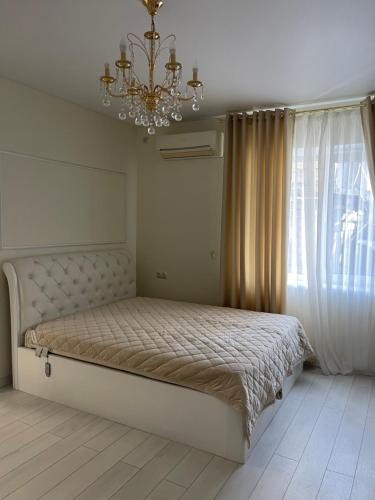 a bedroom with a bed with a chandelier and a window at Квартира в историческом центре Одессы in Odesa