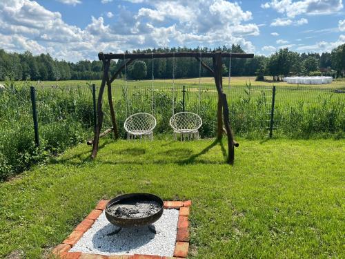a grill in a field with two chairs in the grass at Domek pod jesionami in Ruciane-Nida