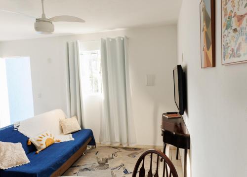 un salon avec un canapé bleu et une télévision dans l'établissement Floripa - MoçamBlue - Casa 2 quartos, 1 km da Reserva Nacional de Surf, perfeita para famílias ou casais, Wi-Fi, garagem e sossego Praia do Moçambique, à Florianópolis