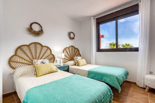 two beds in a room with a window at Oasis in Los Collados - 2BR - Pool & Garden in Águilas