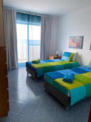 a bedroom with two beds and a large window at A casa da Xã in Almagreira
