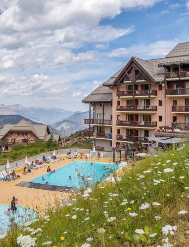 un complexe avec une piscine en face des bâtiments dans l'établissement Valmeinier, appartement 6 pers, pied des pistes, à Le Désert