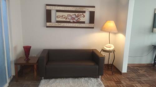 a living room with a brown couch and a lamp at IDEAL Hotel Confort Suite in Piracicaba