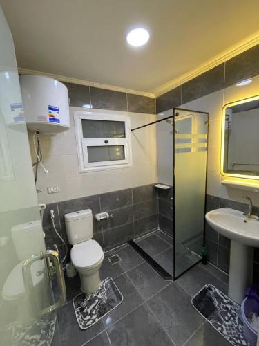 a bathroom with a toilet and a sink at Pyramids Elsewedy home in Ghaţāţī