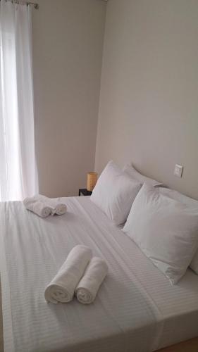 two towels on a white bed with a window at Noma apartment in Gythio